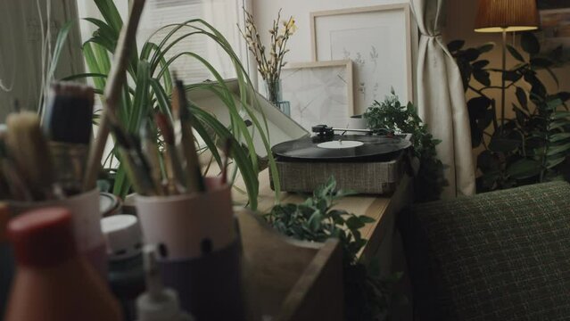 No people shot of retro vinyl player, house plants and many paint brushes at creative messy artist workshop