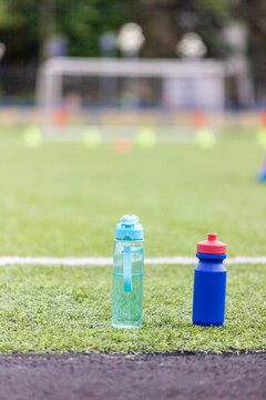Two Sports Water Bottles On A Blurry Background Of A Green Football Field
