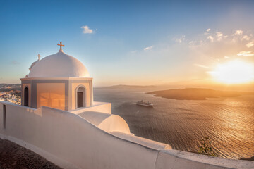 Old Town of Thira on the island Santorini, white church against colorful sunset in Greece