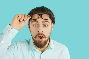 Studio head shot of astonished young man. Handsome man with beard and moustache in white office...