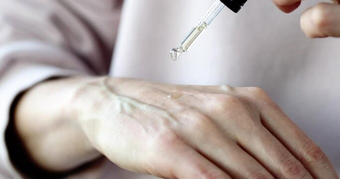 Woman dripping essential oil on skin of hands closeup
