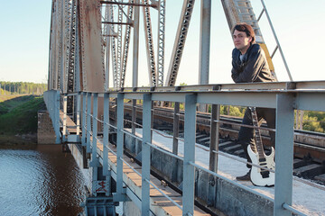 Man with an electric guitar in the industrial landscape outdoors