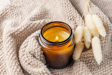 scented burn candle on cotton textyle close up. Aromatherapy cozy atmosphere lifestyle. Autumn warm...