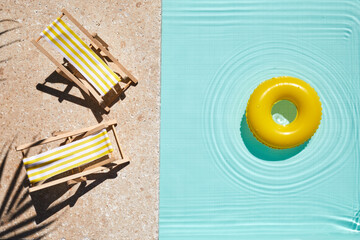Top view swimming pool with yellow chaise lounge and swimming ring. Summer vacation concept.
