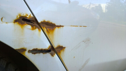 Sheet metal corrosion of old car. Rusty surface, background and damaged texture from road salt. How...