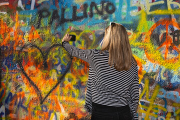 Mujer joven haciéndose una foto con muro de grafiti.