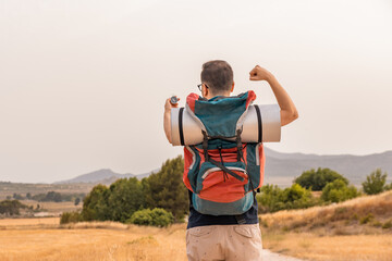 Explorador irreconocible con gesto de alegría y victoria, en la montaña con una brújula. De...