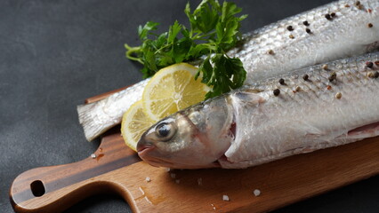 Seafood fresh mullet fish with lime, herbs and spices on a dark background.