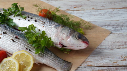 Seafood fresh mullet fish with lime, herbs and spices on a old wooden table.