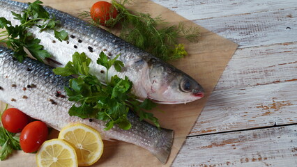 Seafood fresh mullet fish with lime, herbs and spices on a old wooden table.