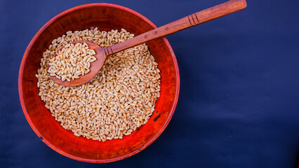 Wooden utensil. Wooden pots. Wheat in Wisden bowl and spoon. Wooden utensils with blue background
