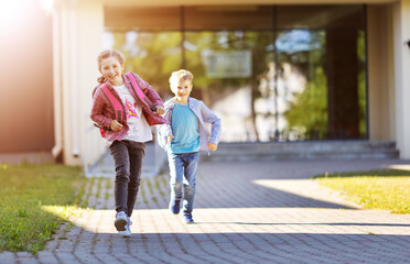 Girl and boy running from school after studying at it.