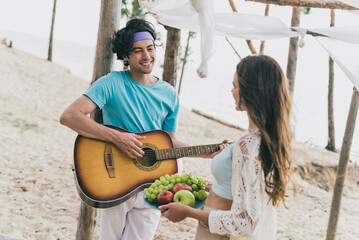 Photo of funny charming young couple wear casual clothes playing guitar eating fruits outside...