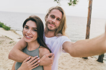 Photo of sweet attractive husband wife walking hugging tacking selfie enjoying summer time outdoors ocean seaside