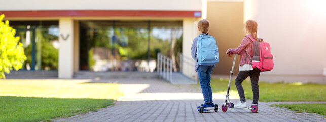 Girl and boy riding by scooters in school to study at it. © candy1812