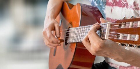 A young man playing string instrument, learning chords practicing music, enjoying