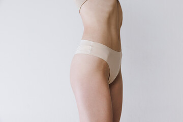 Cropped image of slim female body, belly, buttocks in underwear isolated over grey studio background. Anti-cellulite treatment