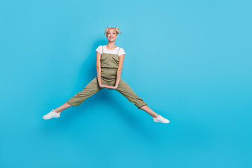 Fototapeta na wymiar Full length photo of impressed millennial blond lady jump wear t-shirt overall footwear isolated on blue background