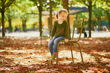 Adorable preschooler girl enjoying nice and sunny autumn day outdoors