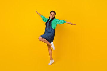Full length portrait of excited cheerful lady raise hands dancing good mood isolated on yellow color background