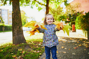 Adorable preschooler girl enjoying nice and sunny autumn day outdoors