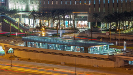Futuristic building of Dubai tram station and shopping mall behind in Dubai Marina aerial night...
