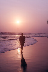 Male model, traveler walking the beach with sunset and ocean background, holiday tropical landscape.