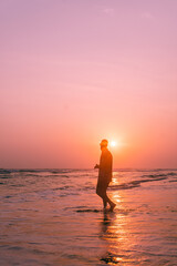 Male model walking on tropical beach at sunset, beautiful holiday landscape.