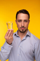 A guy in a blue shirt holds a plastic cup of water in his hands