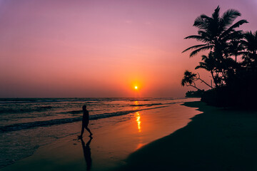 Male model walking on tropical beach at sunset, beautiful holiday landscape.