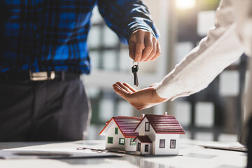 The real estate agent hands the customer the keys to the house after the contract agreement is complete.