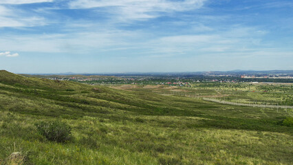 Obraz premium View of the city of Ust-Kamenogorsk (kazakhstan). Summer steppe. Green grass and blue sky. Hills. Cityscape