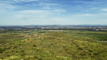 View of the city of Ust-Kamenogorsk (kazakhstan). Summer steppe. Green grass and blue sky. Hills. Cityscape