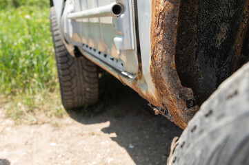 Fototapeta na wymiar Rusty car body damaged by corrosion with hole on threshold