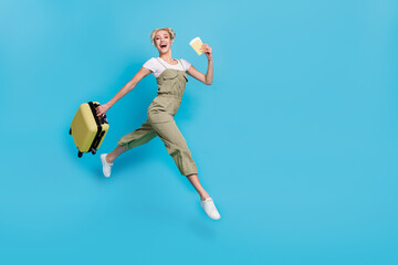 Fototapeta na wymiar Full length photo of impressed young blond lady run with bag passport wear t-shirt overall sneakers isolated on blue background