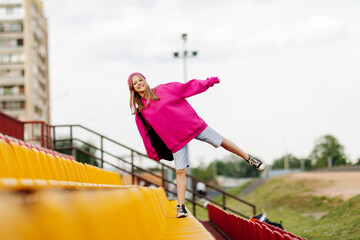 A teenage girl with a backpack walks through the stands of the school stadium