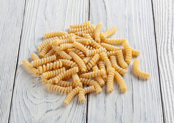 Uncooked fusilli pasta on white wooden background