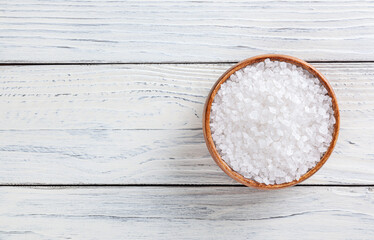 Sea salt in wooden bowl on white wooden table