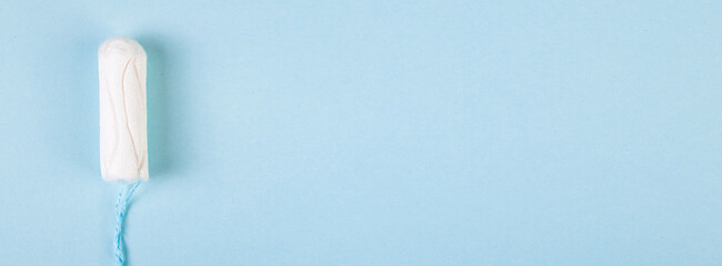 Hygienic cotton tampon on blue background. Feminine menstrual hygiene products.