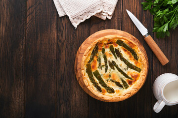 Quiche. Homemade asparagus pie or quiche with cheese and spinach on old dark wooden table background. Top view.