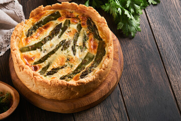 Quiche. Homemade asparagus pie or quiche with cheese and spinach on old dark wooden table...
