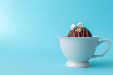 Chocolate bomb with handmade marshmallows in a white cup with milk on a blue background. The place for text is on the right. High-quality photo