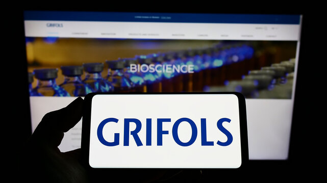 Stuttgart, Germany - 01-30-2022: Person holding cellphone with logo of Spanish pharmaceutical company Grifols SA on screen in front of business webpage. Focus on phone display.