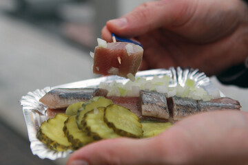 Hand takes a piece of herring with a toothpick. Traditional Dutch food.