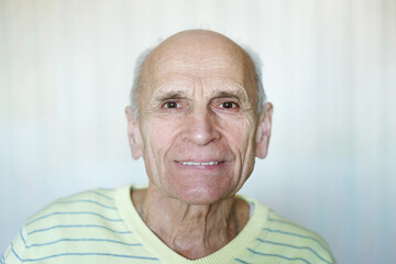 Close up portrait of elder man smiling with teeth and looking in camera with candid look