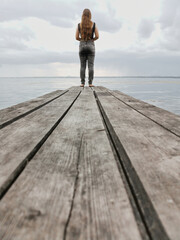  teenage girl stands looking out into the overcast sky. the concept loneliness