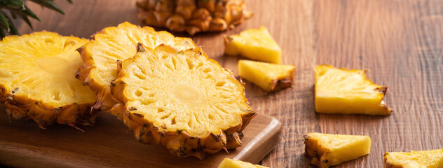 Fresh cut pineapple on a tray over dark wooden table background.