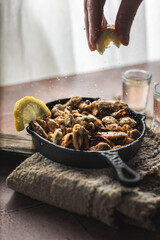 lemon drops on baked mussels in old iron pan backlight side view