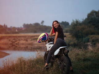 a young woman on a cross - country motorcycle or pit bike at sunset . active recreation