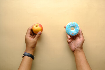 hand holding donuts and apple on hand on blue background 